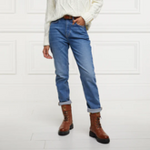 Person wearing blue jeans and brown biker boots against a white background
